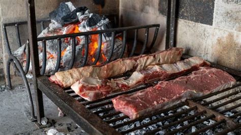 Disposición de las brasas en forma de H o I debajo del cabrito en la parrilla