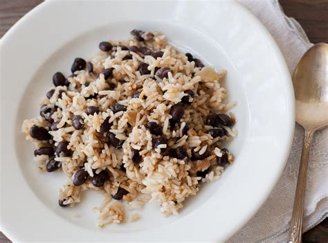 Plato de arroz con porotos negros, pernil deshilachado y rodajas de longaniza