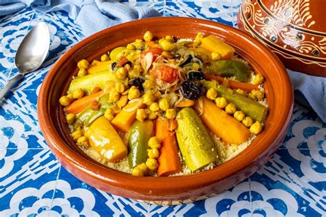 Foto cenital de un plato de cuscús con tiras de pollo, pasas hidratadas y verduras salteadas