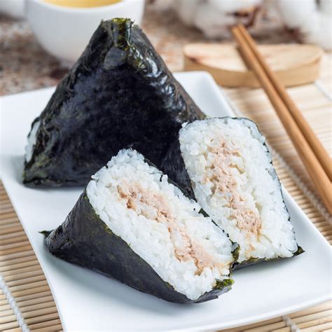 Primer plano de un onigiri siendo envuelto con una tira de alga nori