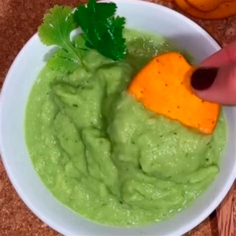 Guacamole cremoso en un bol decorado con tomate y cilantro