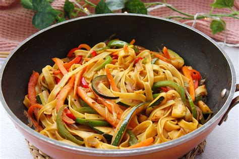 Imagen de un wok humeante con tallarines salteados, verduras frescas y salsa de soja brillante.