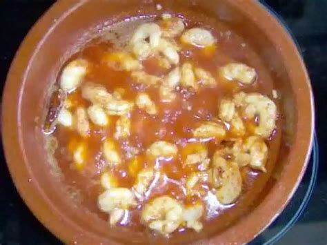 Fotografía gastronómica de un plato de pollo al pil pil servido en cazuela de barro, decorado con perejil fresco y acompañado de tostadas crocantes.