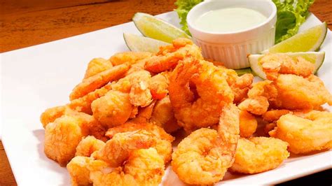 Plato de camarones apanados con salsa de ajo y vegetales