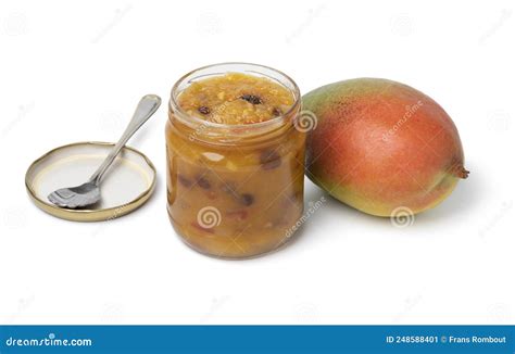 Chutney de mango en un frasco de vidrio sobre una tabla de madera, con crackers y queso