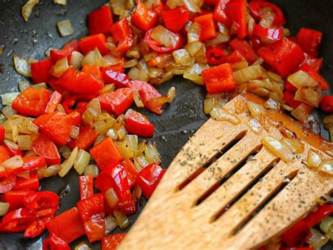 Pimientos y cebolla salteándose en una sartén grande