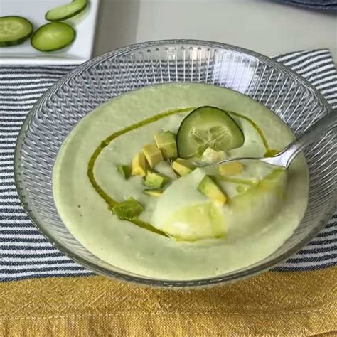 Sopa fría de pepino servida en cuenco decorada con semillas y hierbas frescas