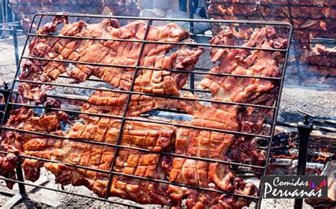 Chancho al palo cocinándose en una parrilla rústica al aire libre con brasas.