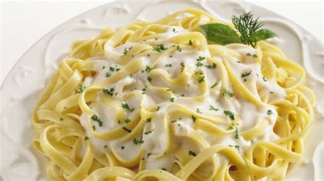 Plato de pasta servido con una abundante y cremosa salsa blanca, espolvoreado con queso parmesano rallado.