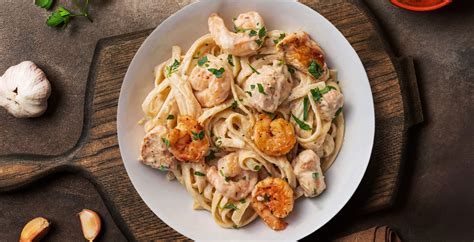Fotografía profesional del plato terminado de fettuccini con pollo y camarones salteados con una textura cremosa.