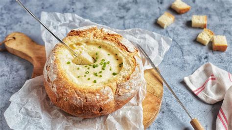 Foto de una fondue de queso burbujeante servida dentro de un pan campesino