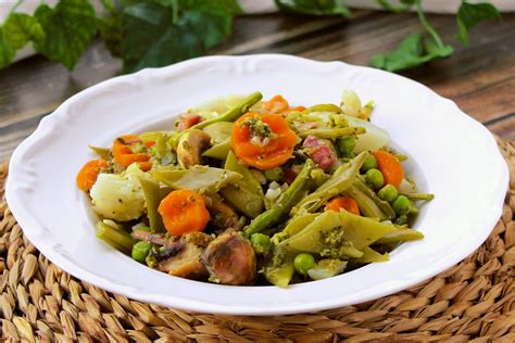 Foto de un plato de guisantes con jamón o una menestra de verduras.