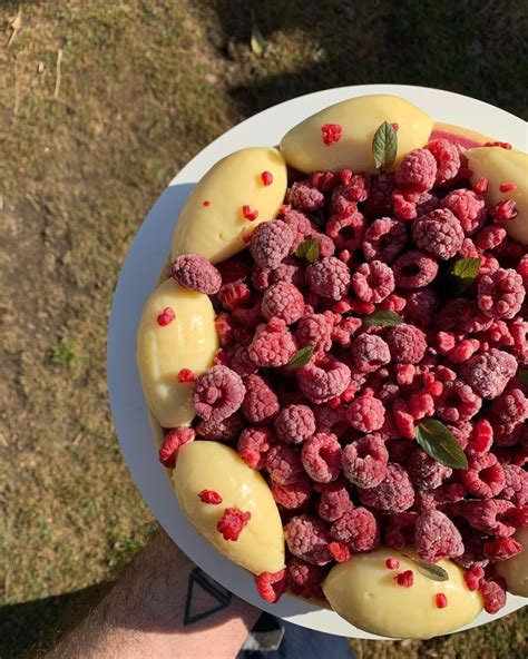 Fotografía cenital de una tarta de frambuesas decorada con frutos frescos y chocolate blanco