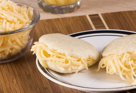 Plato final de arepas rellenas de queso, mostrando el queso derretido al ser cortadas.