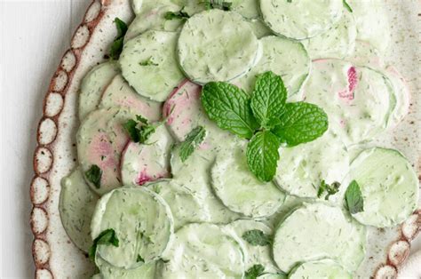 detalle de rodajas finas de pepino con aderezo cremoso y hierbas frescas
