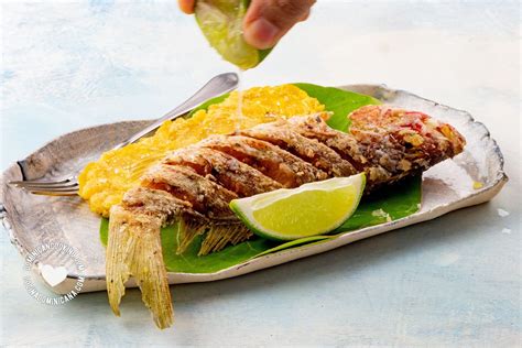 Plato de pescado frito dorado y crujiente acompañado de limón
