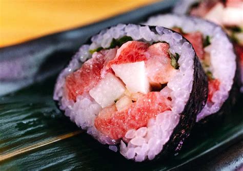 Fotografía detallada de láminas de Gari rosado acompañando una pieza de sushi nigiri.