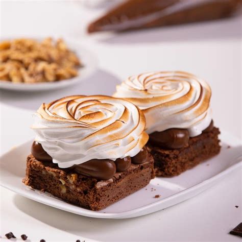 Foto de un trozo de brownie con dulce de leche y merengue servido en un plato