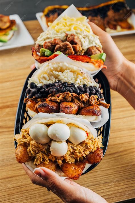 Fotografía de una mesa tradicional venezolana con empanadas recién fritas y diversas salsas como guasacaca y ajicero.