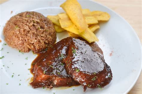 Plato de Posta Negra Cartagenera con arroz con coco y tajadas de plátano maduro