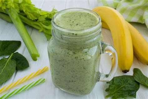 Vaso de un batido verde recién hecho, con espinacas y otras frutas visibles, en un entorno de cocina.