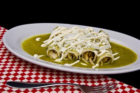Plato de enchiladas verdes de queso recién hechas, decoradas con crema y queso
