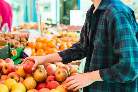 Persona comprando frutas y verduras frescas en un mercado.