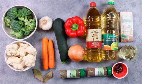 Mesa con ingredientes frescos para el escabeche: verduras, hierbas, ajo, aceite, vinagre