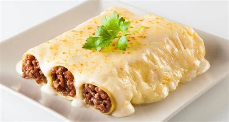 Foto de canelones de carne en una fuente con bechamel, listos para hornear