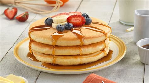 Foto de una pila de panqueques americanos esponjosos con sirope de arce y frutas
