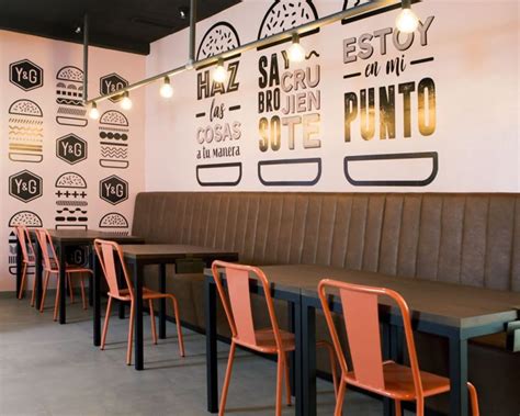 Fotografía de un interior moderno y acogedor de una hamburguesería con decoración temática y clientes disfrutando.