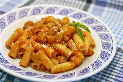 plato de macarrones con berenjena decorado con aceitunas y albahaca fresca