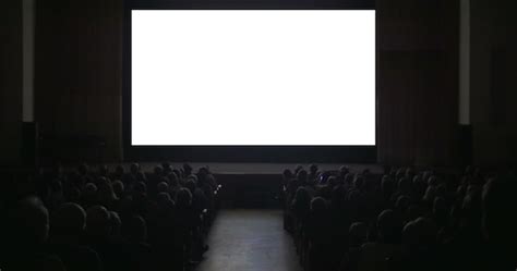 Imagen de una sala de cine oscura con la pantalla encendida y un cubo de palomitas de maíz en primer plano