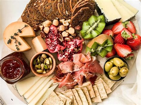 Mesa de picoteo con opciones saludables como pastas vegetales, frutas y panes integrales.