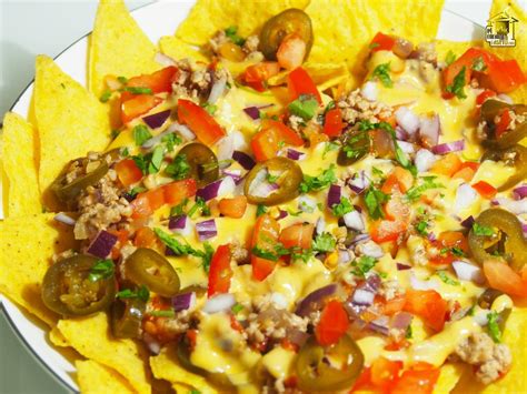 Imagen de una fuente con nachos dorados cubiertos con pollo desmenuzado, queso fundido, guacamole fresco y pico de gallo.