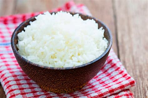 Arroz blanco cocido y aderezado en un bol de madera, con una cuchara de madera