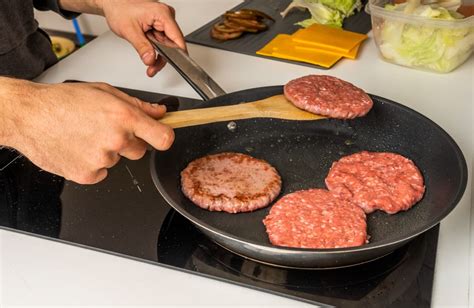 Persona cocinando hamburguesas vegetarianas en una sartén
