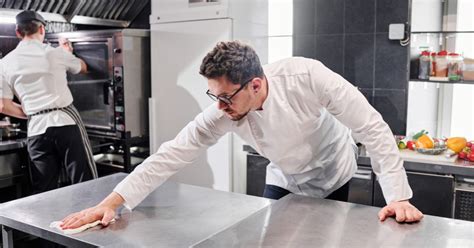 Equipo de limpieza profesional en una cocina de restaurante limpiando un derrame