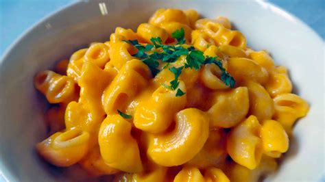 Una foto de unos macarrones con queso vegano cremoso y de color anaranjado, espolvoreados con perejil fresco.