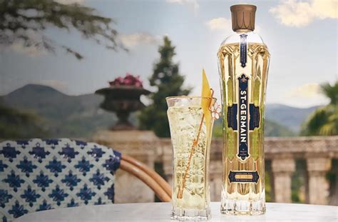 Un St-Germain Spritz recién preparado en una copa de vino, decorado con un twist de limón y flores comestibles