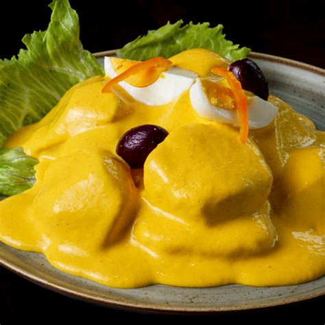 Foto de Papa a la Huancaína con papas cocidas cubiertas de salsa amarilla cremosa, decoradas con huevo y aceitunas