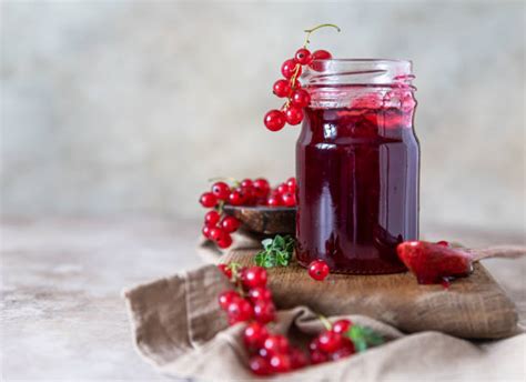 Variedad de productos de grosella: bayas frescas, mermelada en tarro, té en taza