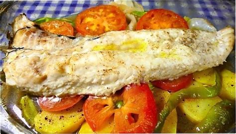 Fotografía de un plato de pescado al horno servido con una colorida selección de verduras salteadas y minihortalizas.