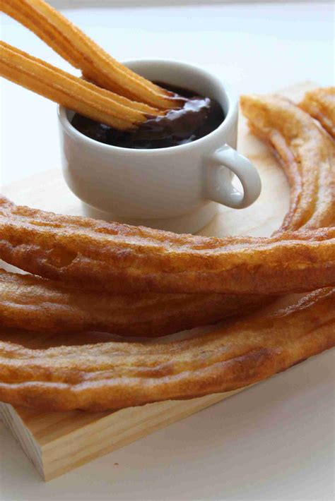 Foto de churros recién hechos, dorados y crujientes, exhibidos en la vitrina de una cafetería.