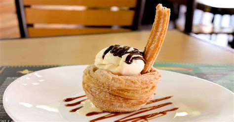 Fotografía apetitosa de un sándwich de churro relleno de helado de vainilla con trozos de fruta.