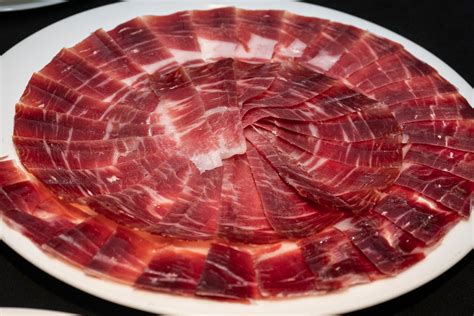Foto de un jamón ibérico de bellota de alta calidad, cortado en finas lonchas