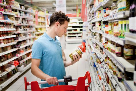 Foto de una persona eligiendo un paquete de galletas en el supermercado, enfocándose en la etiqueta.