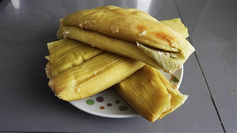 Manos elaborando humitas, rellenando chalas de maíz