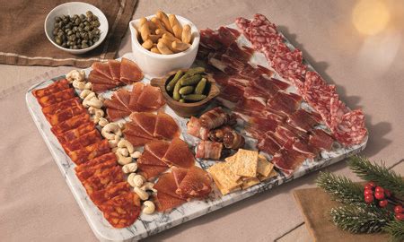 Foto: Presentación elegante de una tabla de embutidos con jamón ibérico, quesos variados y frutos secos.