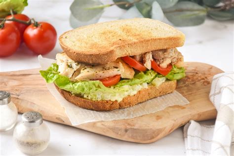 Fotografía temática de un chef utilizando mayonesa Kraft galón para preparar un sándwich gourmet en un entorno de cocina profesional.